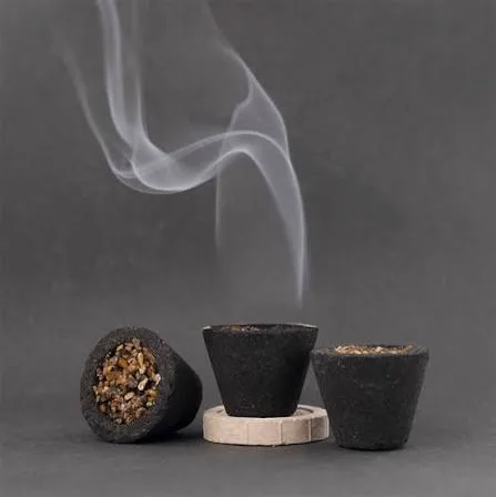 Dark sambrani cups releasing dense aromatic smoke on a stone holder