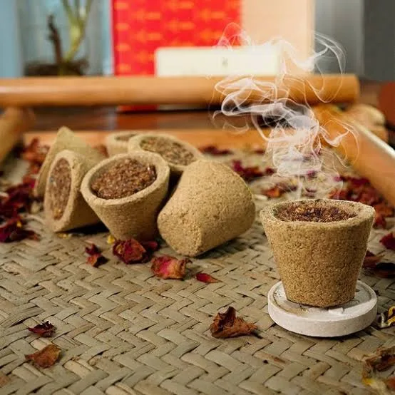 Sambrani cow dung cups smouldering with fragrant smoke on a woven mat
